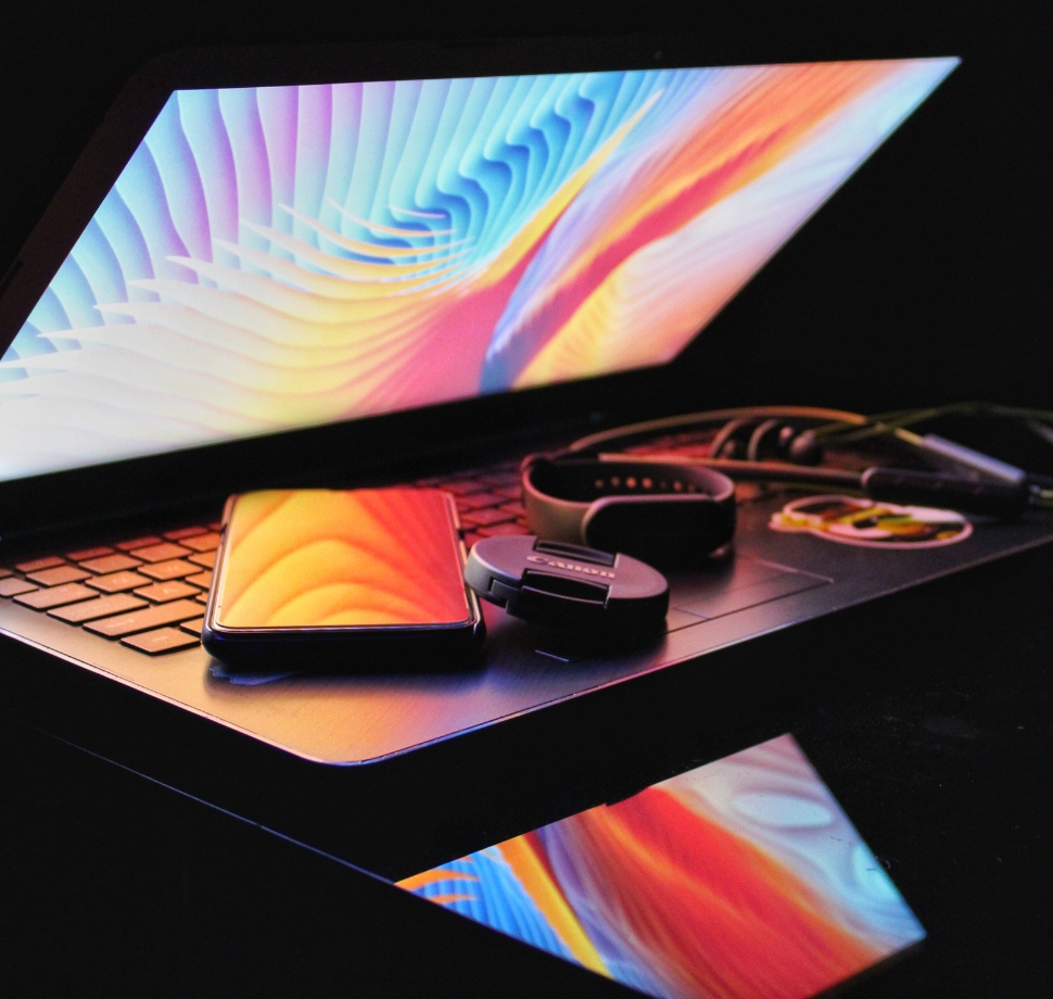 Halb aufgeklappter Laptop mit Smartphones und Smartwatches
